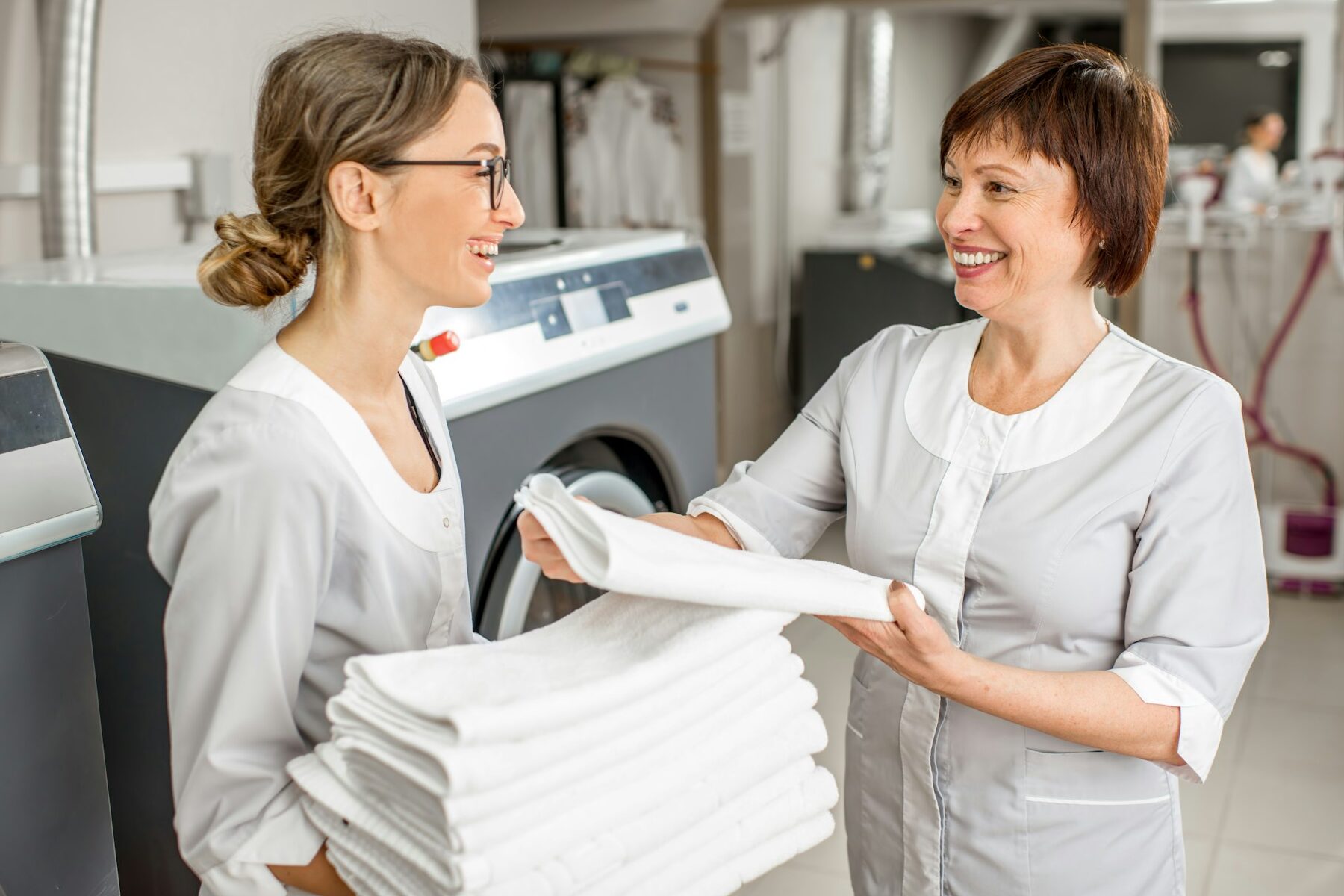 Senior washwoman with young assistant in the laundry
